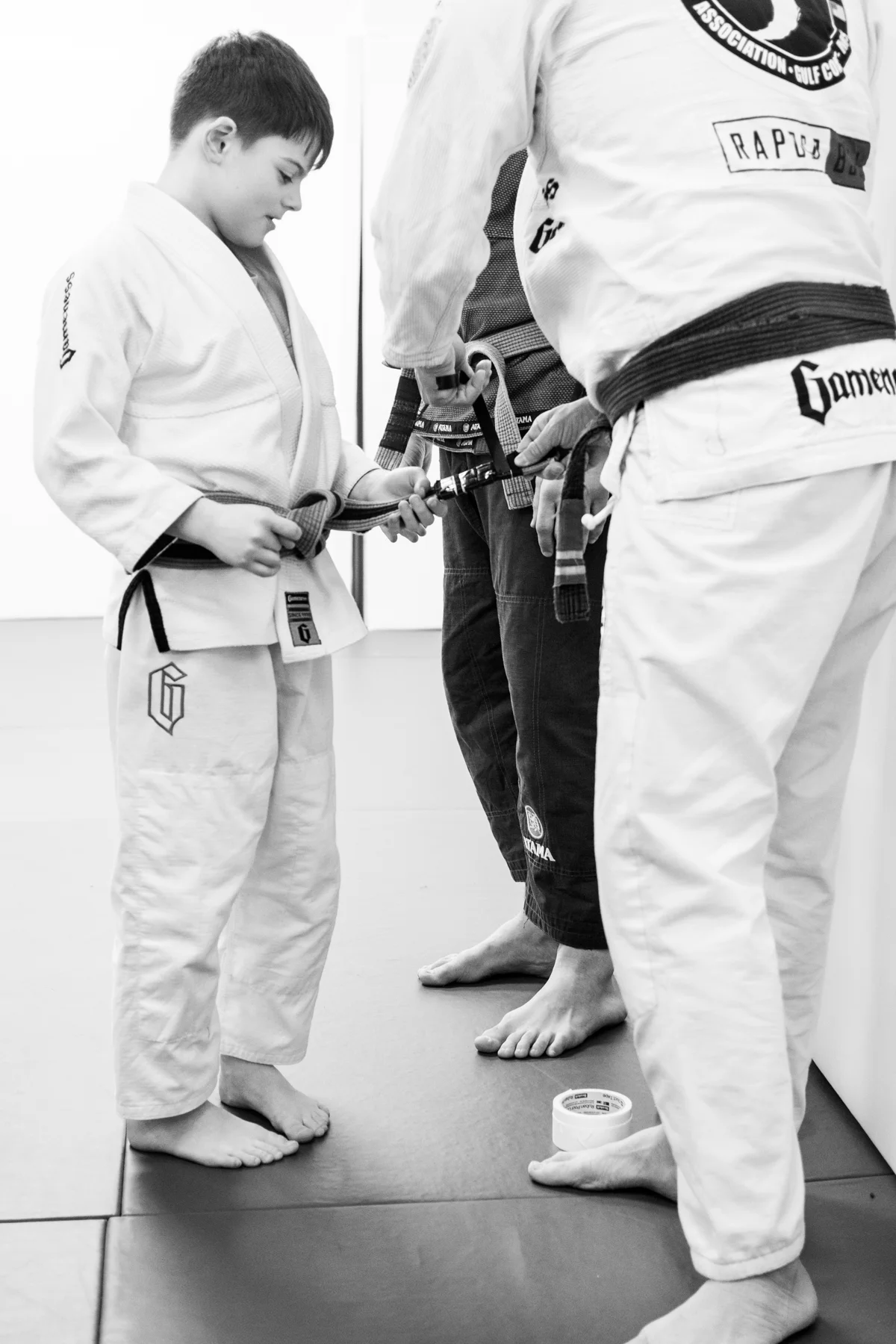 A young student receiving a new belt on the mats